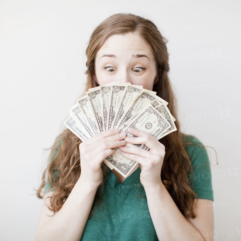 Excited young woman holding fan made up from us dollar banknotes. 
Photo: Jessica Peterson