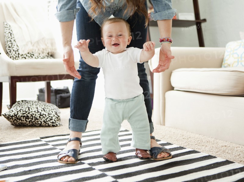 Young mother assisting baby boy (6-11 months) in his first steps. 
Photo: Jessica Peterson