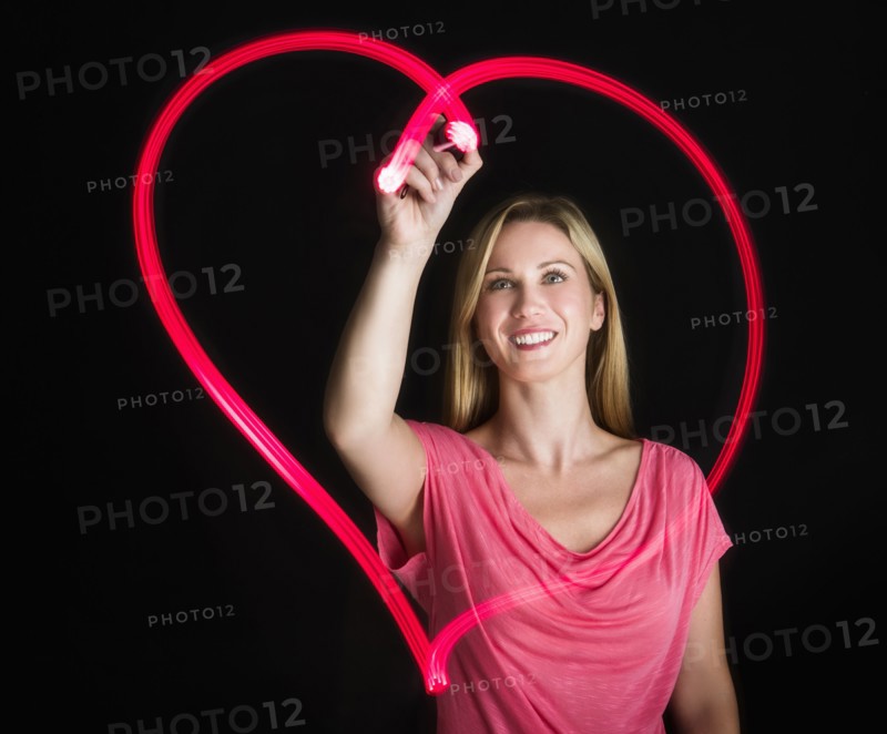 Woman drawing heart on black background.