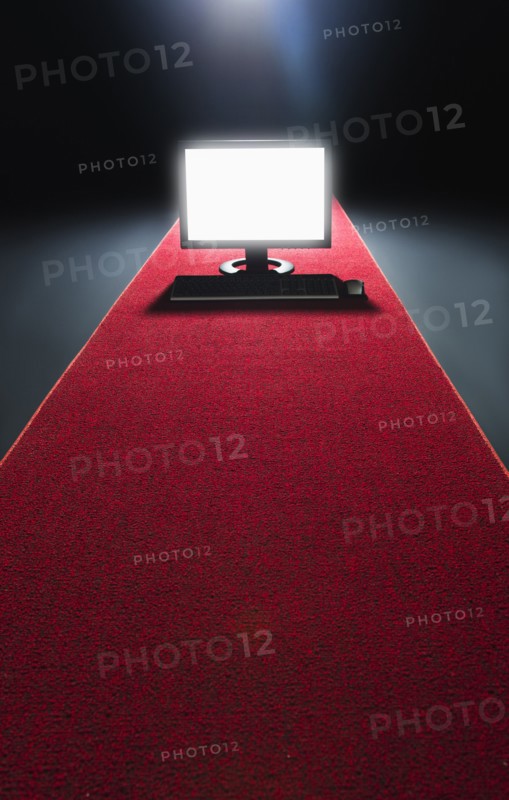 Studio shot of glowing computer on red carpet.