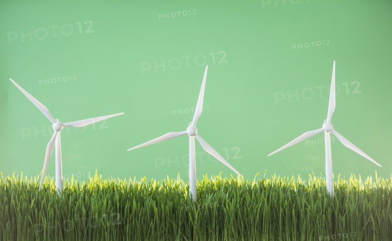 Model wind turbines in grass on green background.
