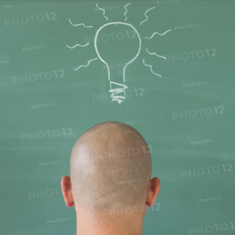 Man in front of blackboard with drawing depicting Lightbulb.
