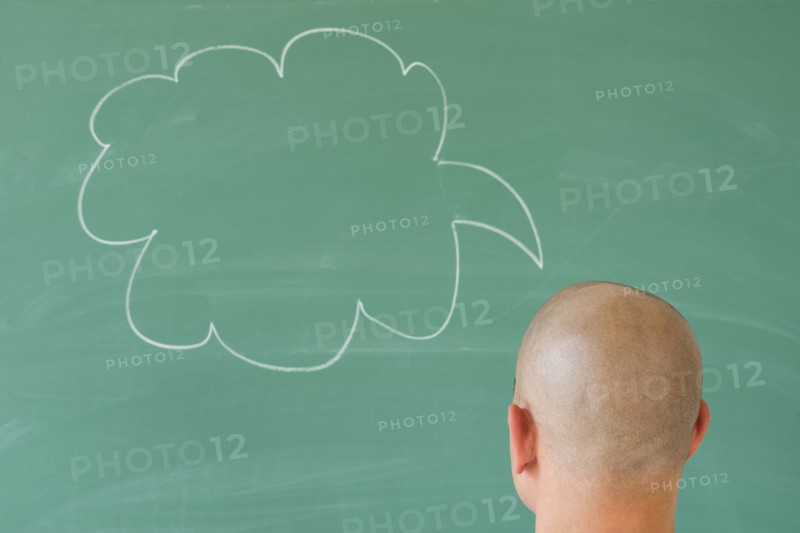 Man in front of blackboard with drawing depicting speech bubble.