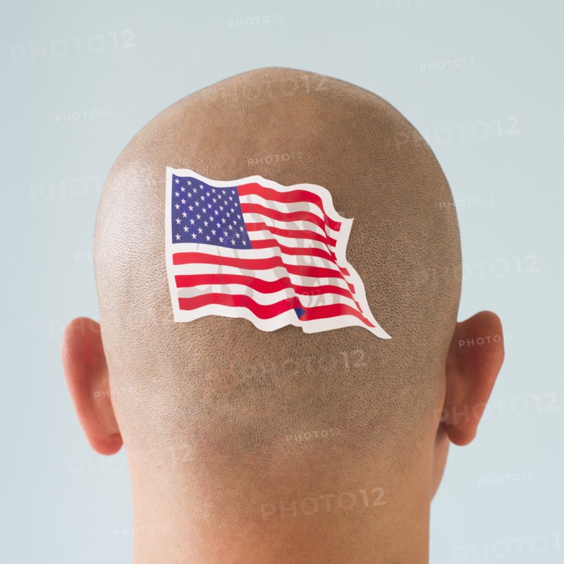 Back view of man with American flag tattoo on head.