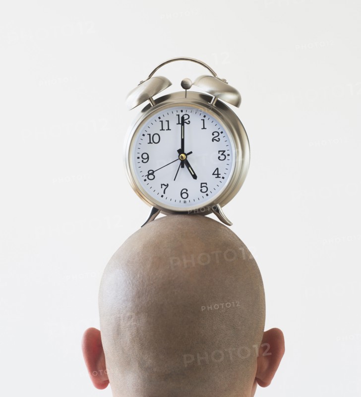 Back view of man with alarm clock on shaved head.