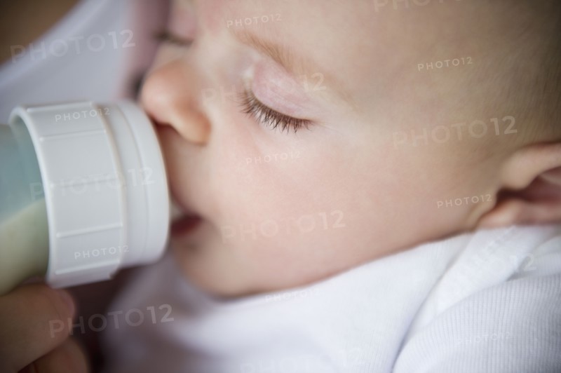 Mother feeding baby boy (2-5 months) using feeding bottle. Photo : Jamie Grill
