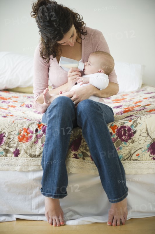 Mother feeding baby boy (2-5 months) using feeding bottle. Photo : Jamie Grill