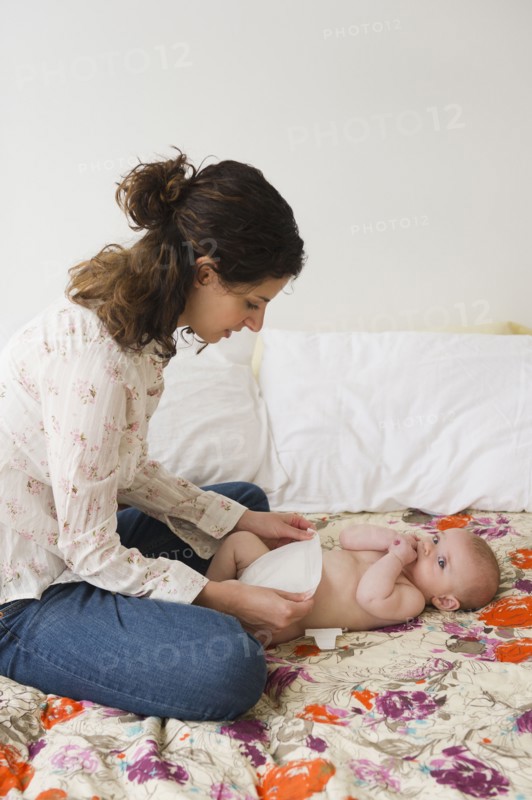 Mother changing baby boy (2-5 months) . Photo : Jamie Grill