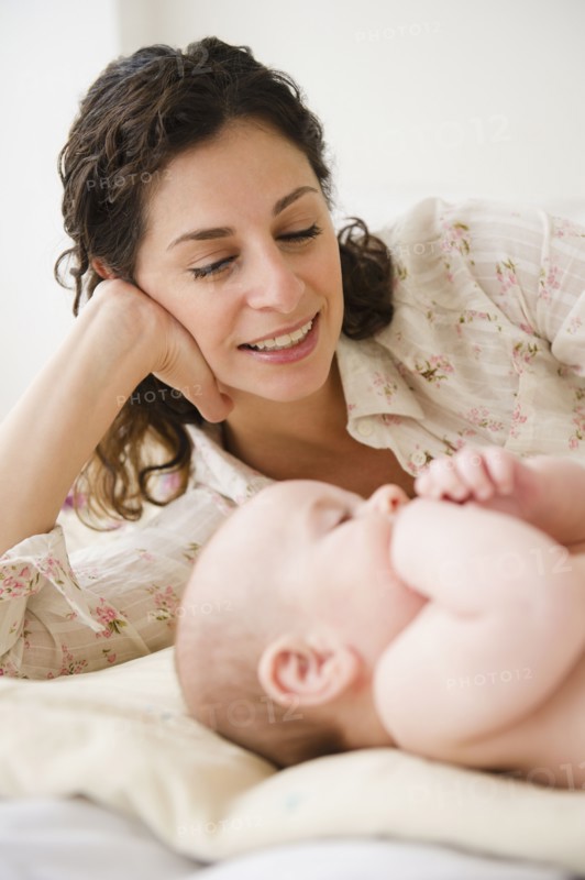 Mother and baby boy (2-5 months) plying together on bed. Photo: Jamie Grill