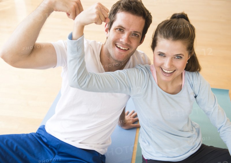 Happy young couple flexing muscles . Photo : Jamie Grill