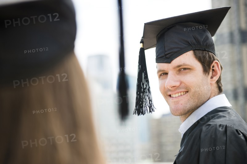 Young man and woman wearing graduation gowns. Photo: Jamie Grill