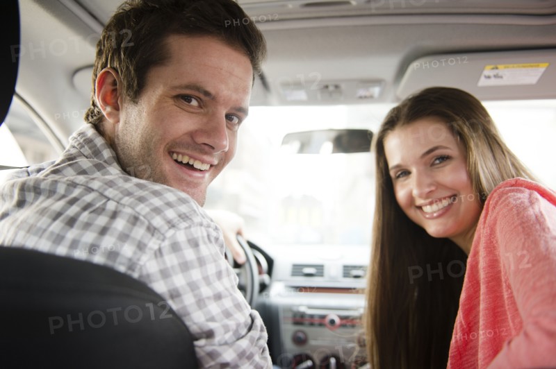 Happy young couple sitting in car. Photo : Jamie Grill