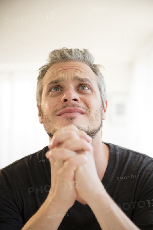 Mid adult man in praying gesture. Photo: Jamie Grill