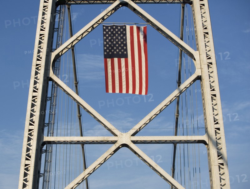 USA, New York City, American flag flowing on bridge span. Photo: fotog