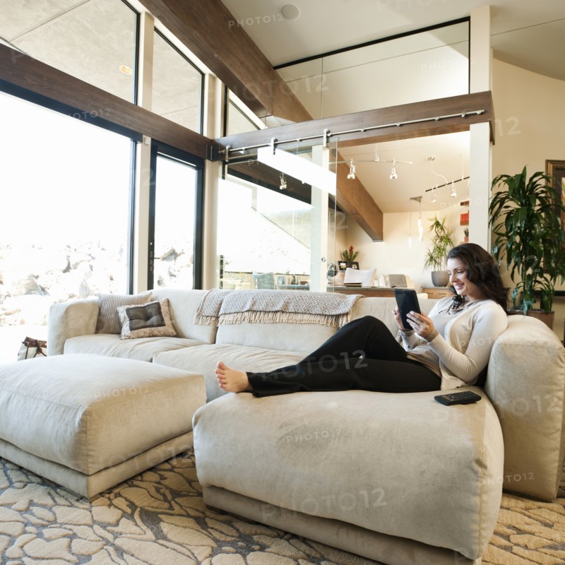 Woman using tablet while sitting on couch.