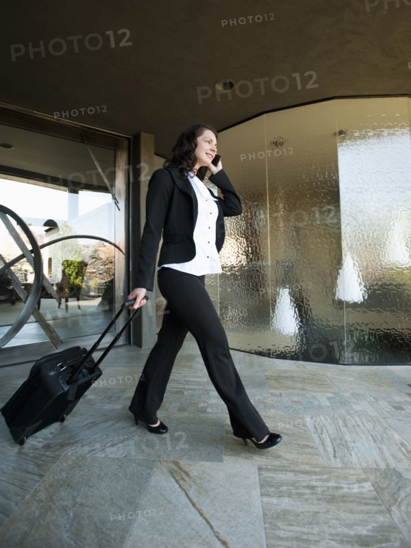 Woman leaving house with piece of luggage.