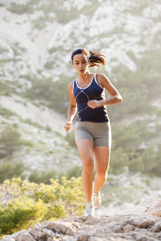 France, Marseille, Young woman jogging on rocky terrain. Photo : Mike Kemp