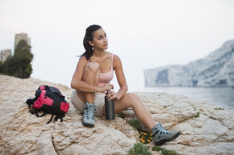 France, Marseille, Female hiker resting on rocky beach. Photo: Mike Kemp