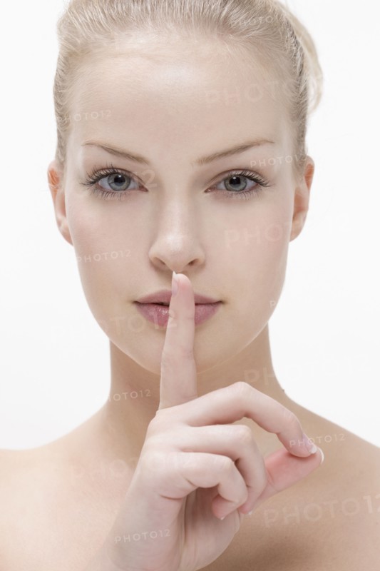 Young woman pressing finger against mouth. Photo : Jan Scherders