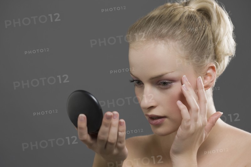 Beauty portrait of woman using powder compact. Photo : Jan Scherders