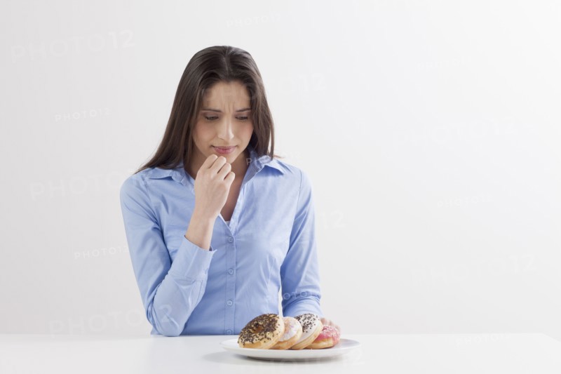 Studio shot of woman looking at donuts. Photo: Jan Scherders