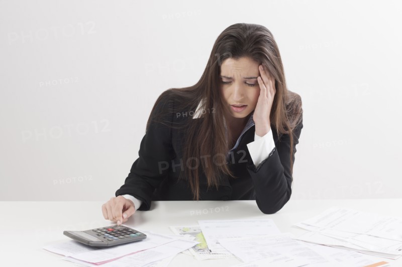 Studio shot of businesswoman with calculator and bills. Photo: Jan Scherders