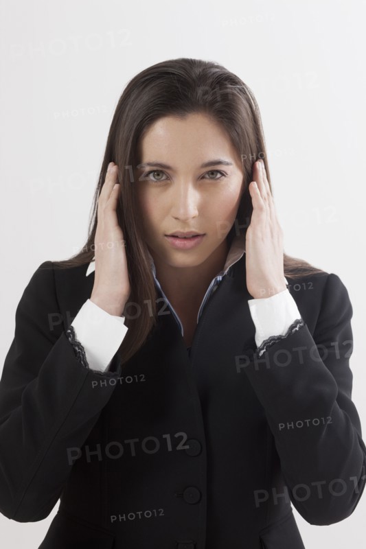 Portrait of young woman with hands covering ears, studio shot. Photo: Jan Scherders