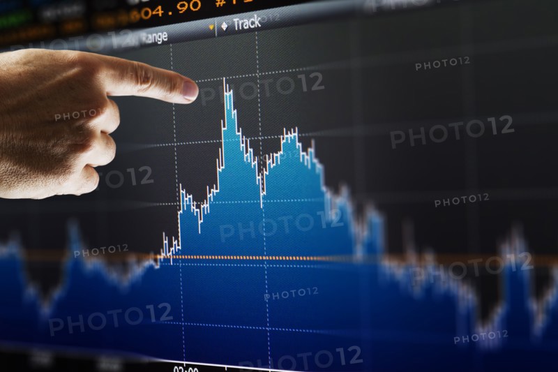 Hand pointing at financial graph, studio shot.