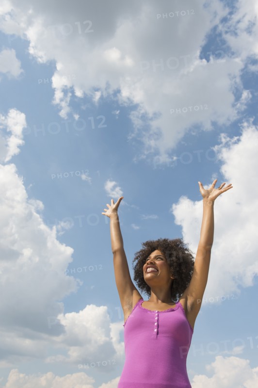 Woman stretching under blue sky.