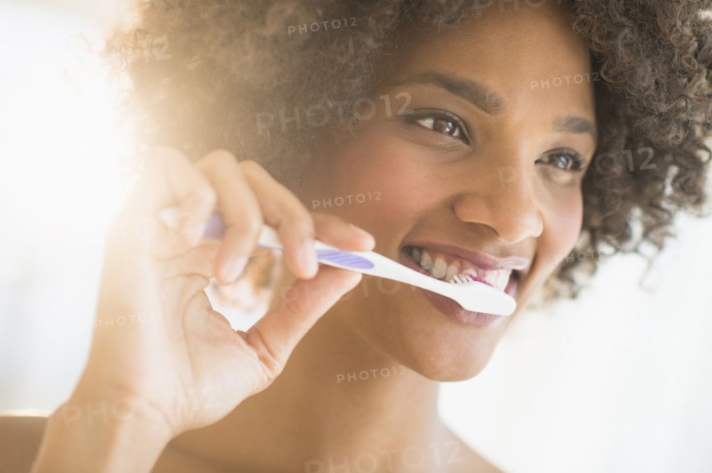 Beauty portrait of woman brushing teeth, studio shot.