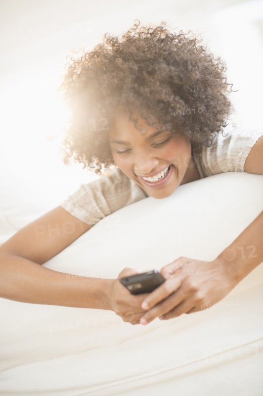 Woman relaxing on sofa using cell phone.