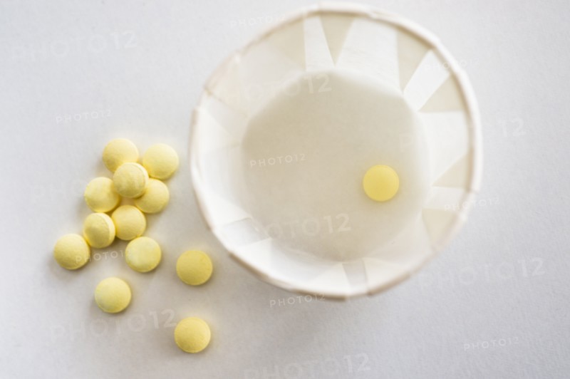 Yellow pills with cup, studio shot.