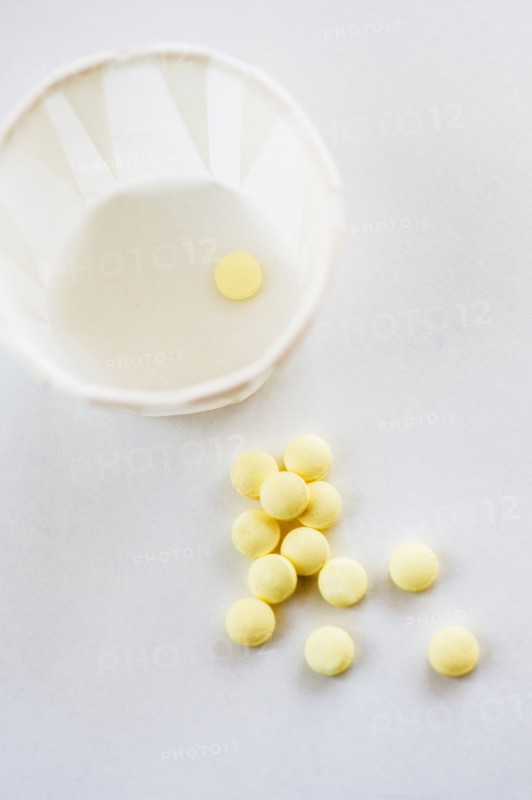 Yellow pills with cup, studio shot.