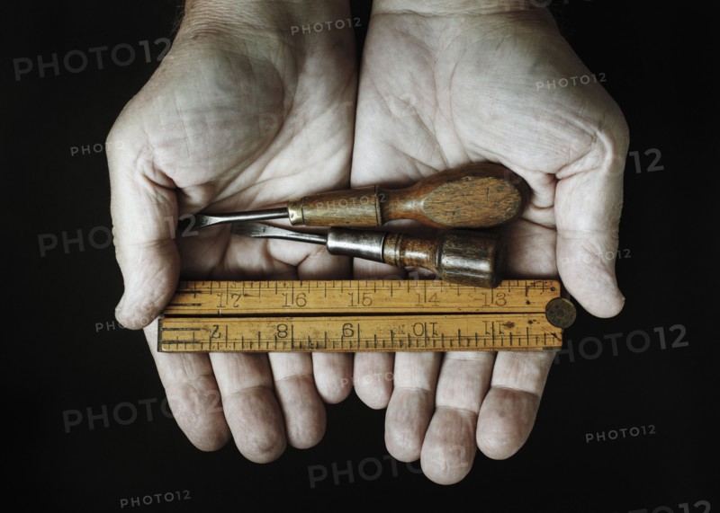 Studio shot of hands holding antique tools.