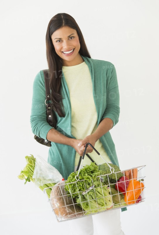 Studio shot of woman holding shopping basket with vegetables.