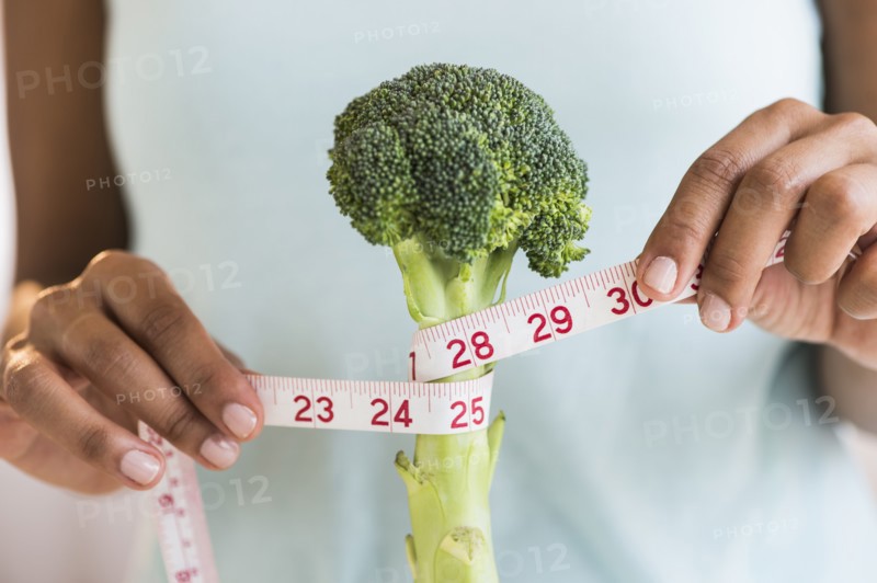 Woman measuring broccoli .