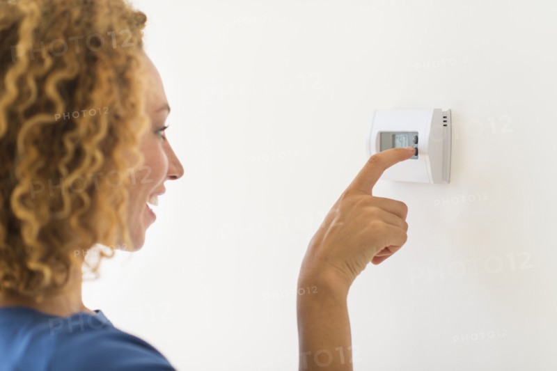 Young woman setting air conditioning.