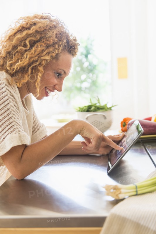 Young woman using digital tablet in kitchen.