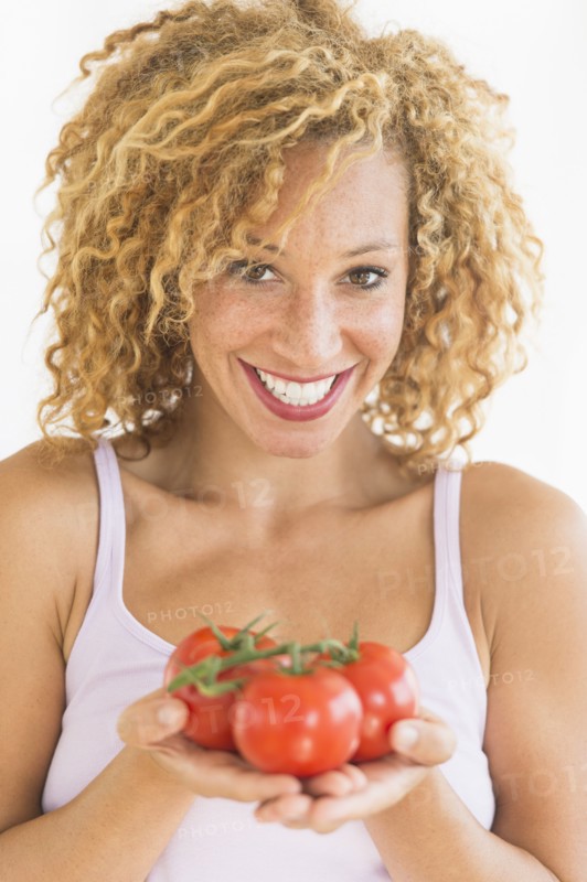 Portrait of young woman holding tomatoes.