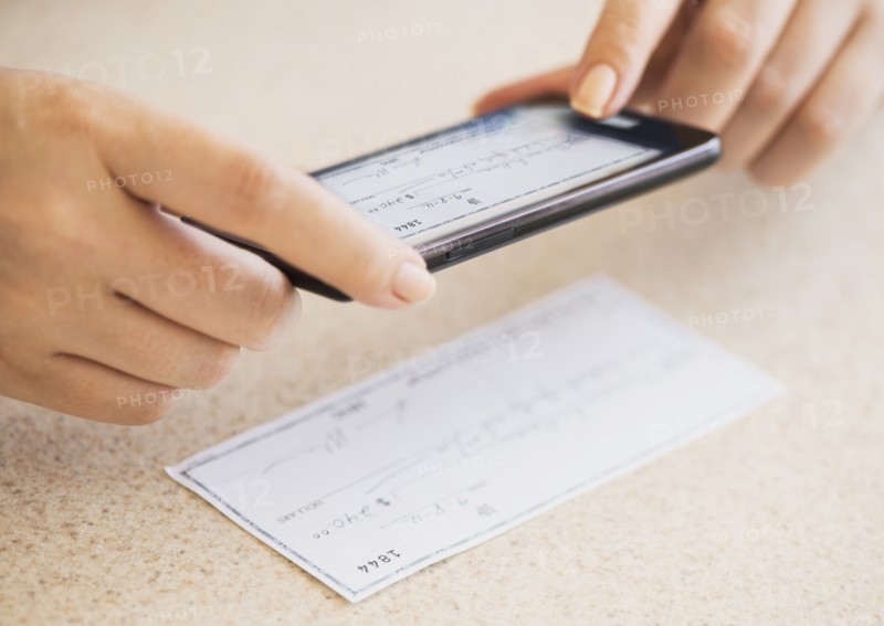 Close up of woman's hand doing online banking with mobile phone.