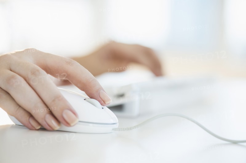Close up of woman's hands using computer keyboard and computer mouse.