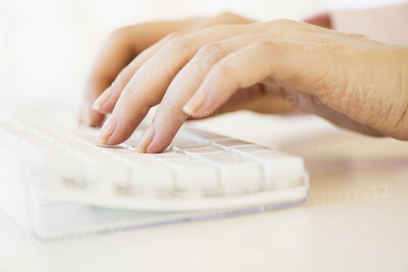 Close up of woman's hands typing on computer keyboard .