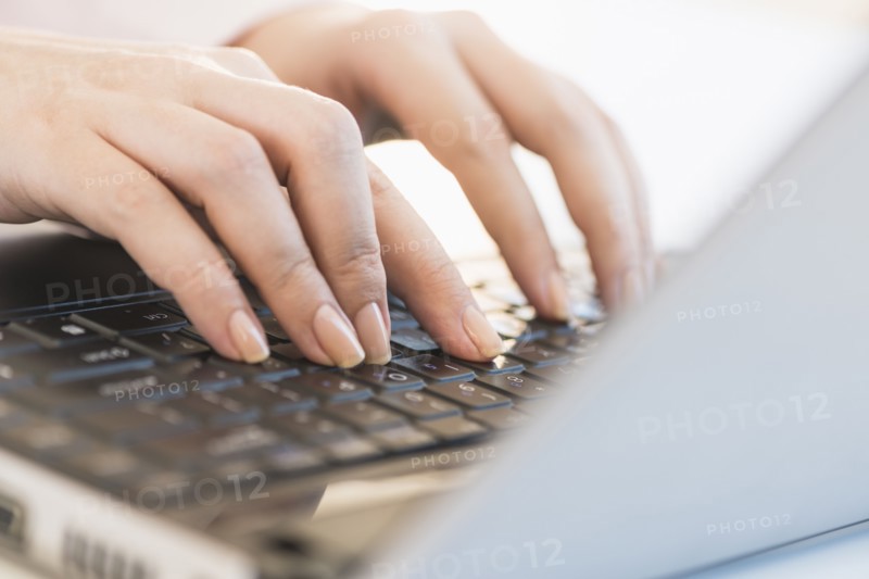 Close up of woman's hands typing on computer keyboard .