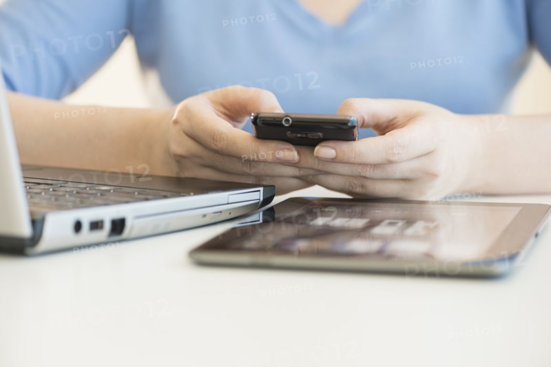 Close up of woman's hands using multiple devices.