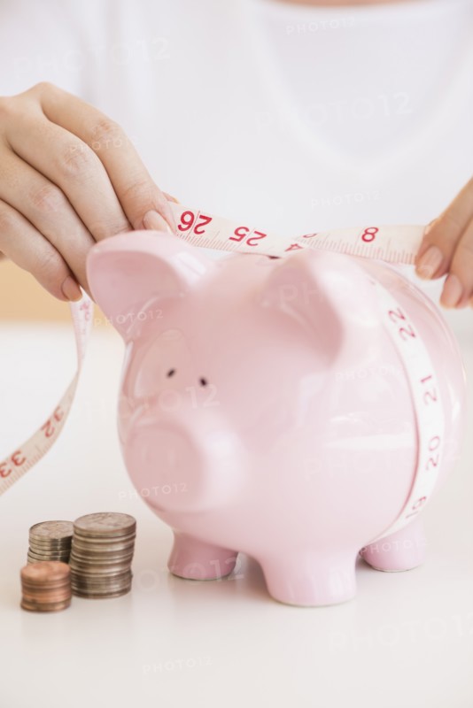 Woman measuring piggybank.