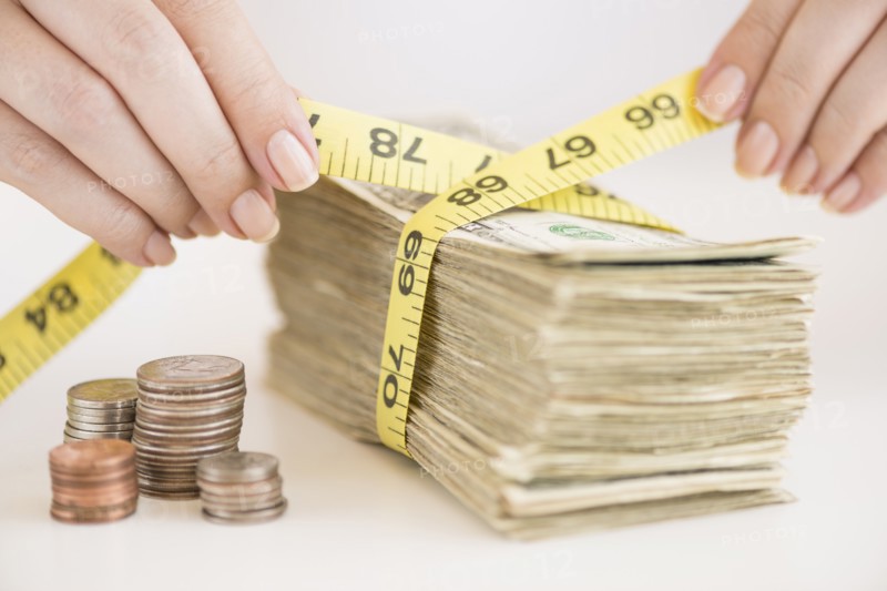 Woman measuring bunch of banknotes.