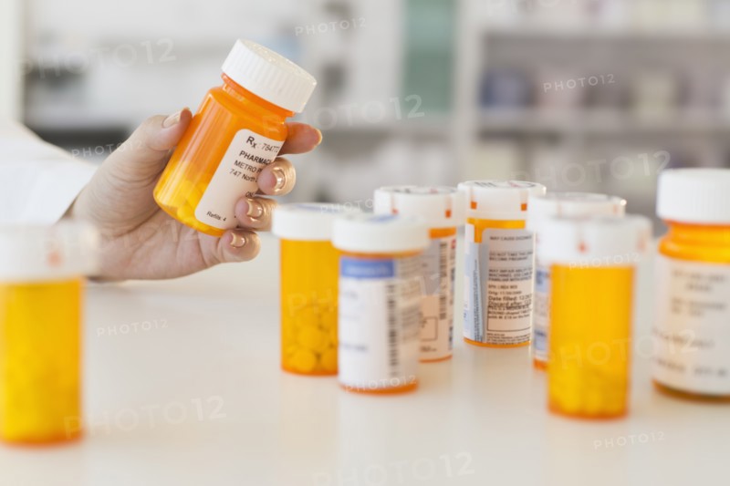 Pharmacist holding pill bottle.