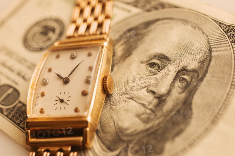 Studio shot of banknote and gold watch.
