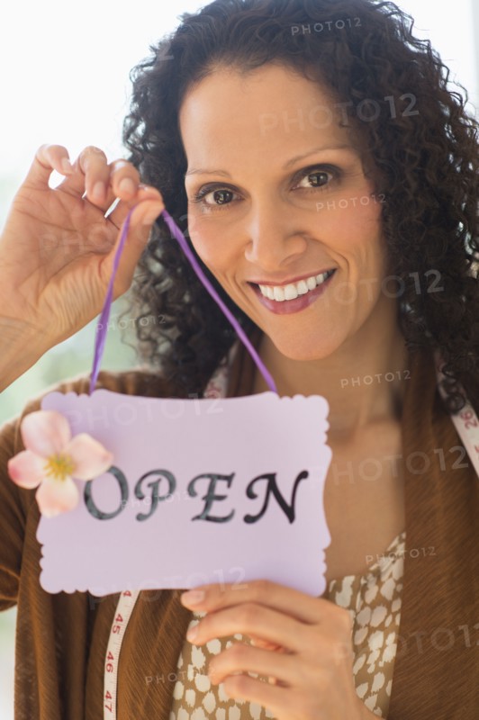 Portrait of woman holding open sign.