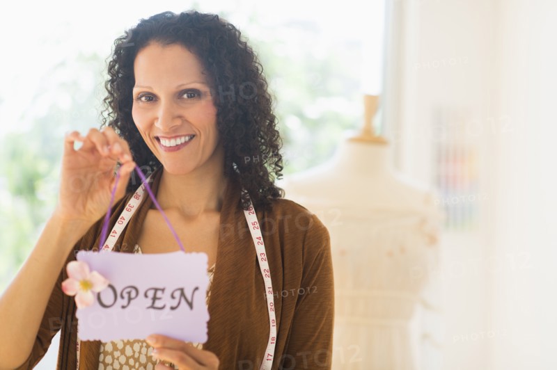 Portrait of woman holding open sign.